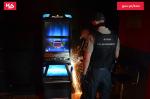 Dwaj funkcjonariusze SCS stoją przed automatem do gier.